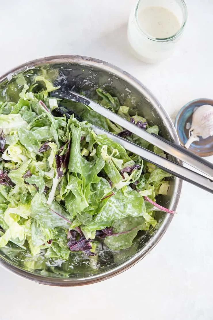 Large Caesar Salad in a mixing bowl with caesar dressing