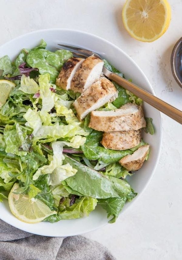 Balsamic Baked Chicken Caesar Salad in a bowl with a napkin and half a lemon