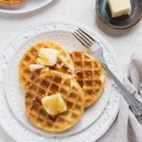 top down photo of two plates of sourdough waffles with butter and honey