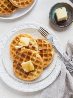 top down photo of two plates of sourdough waffles with butter and honey
