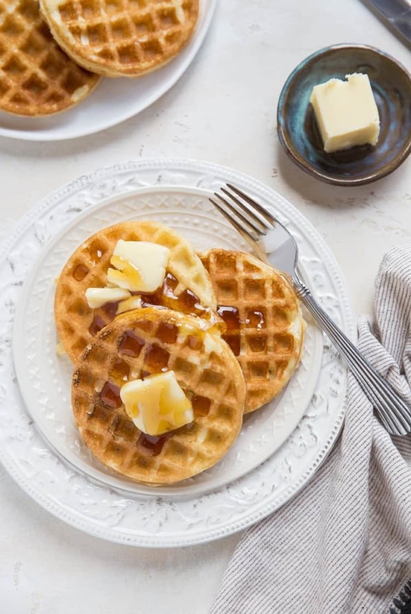 top down photo of two plates of sourdough waffles with butter and honey