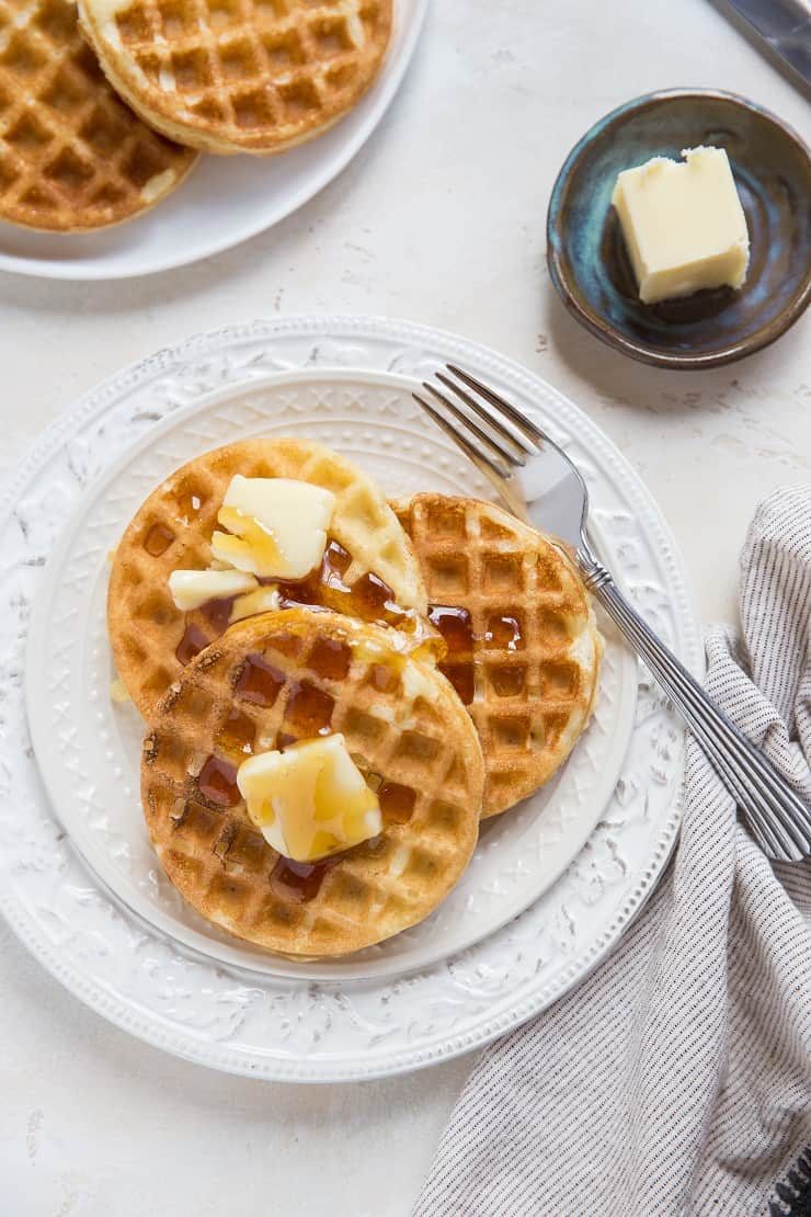 top down photo of two plates of sourdough waffles with butter and honey