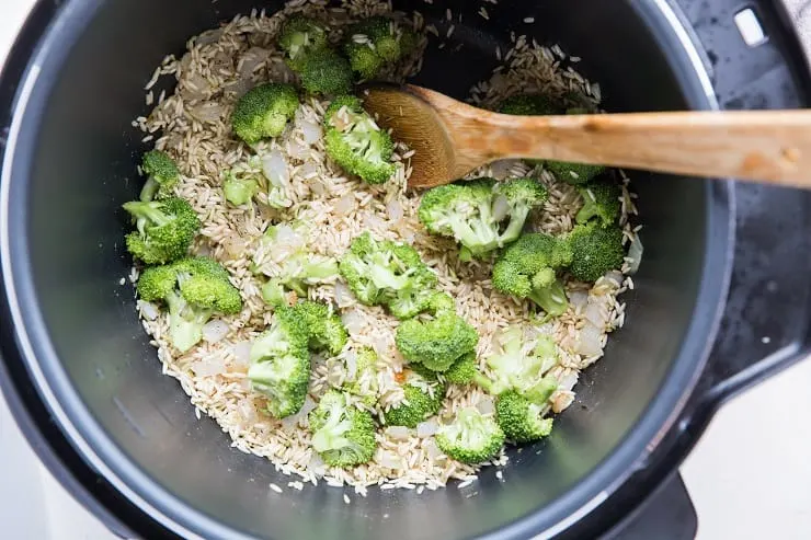 Instant Pot with rice, onion, seasoning, and broccoli in it
