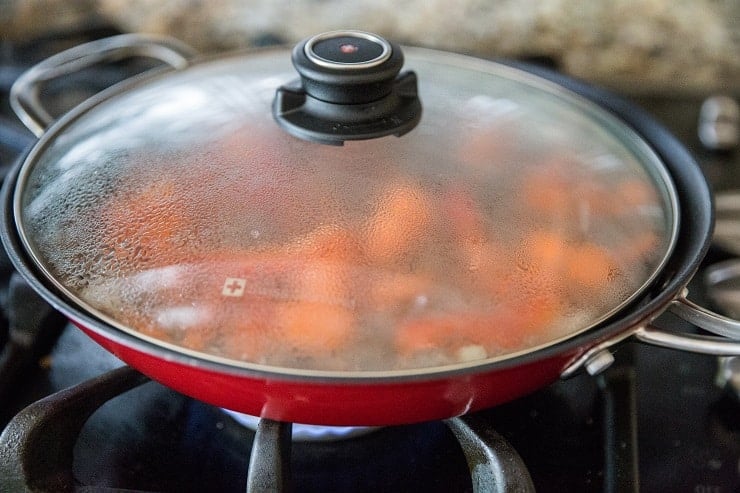 Skillet of ground beef and vegetables covered with a lid