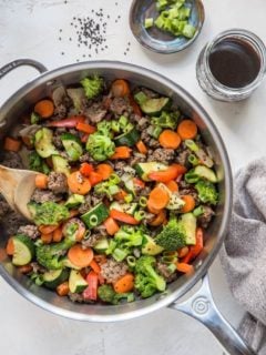 30-Minute Teriyaki Beef Skillet with Vegetables - a skillet, a napkin, a jar of teriyaki sauce and a bowl of chopped green onion