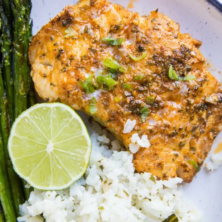 Plate of baked cod with asparagus and cauliflower rice. Ready to eat for dinner!