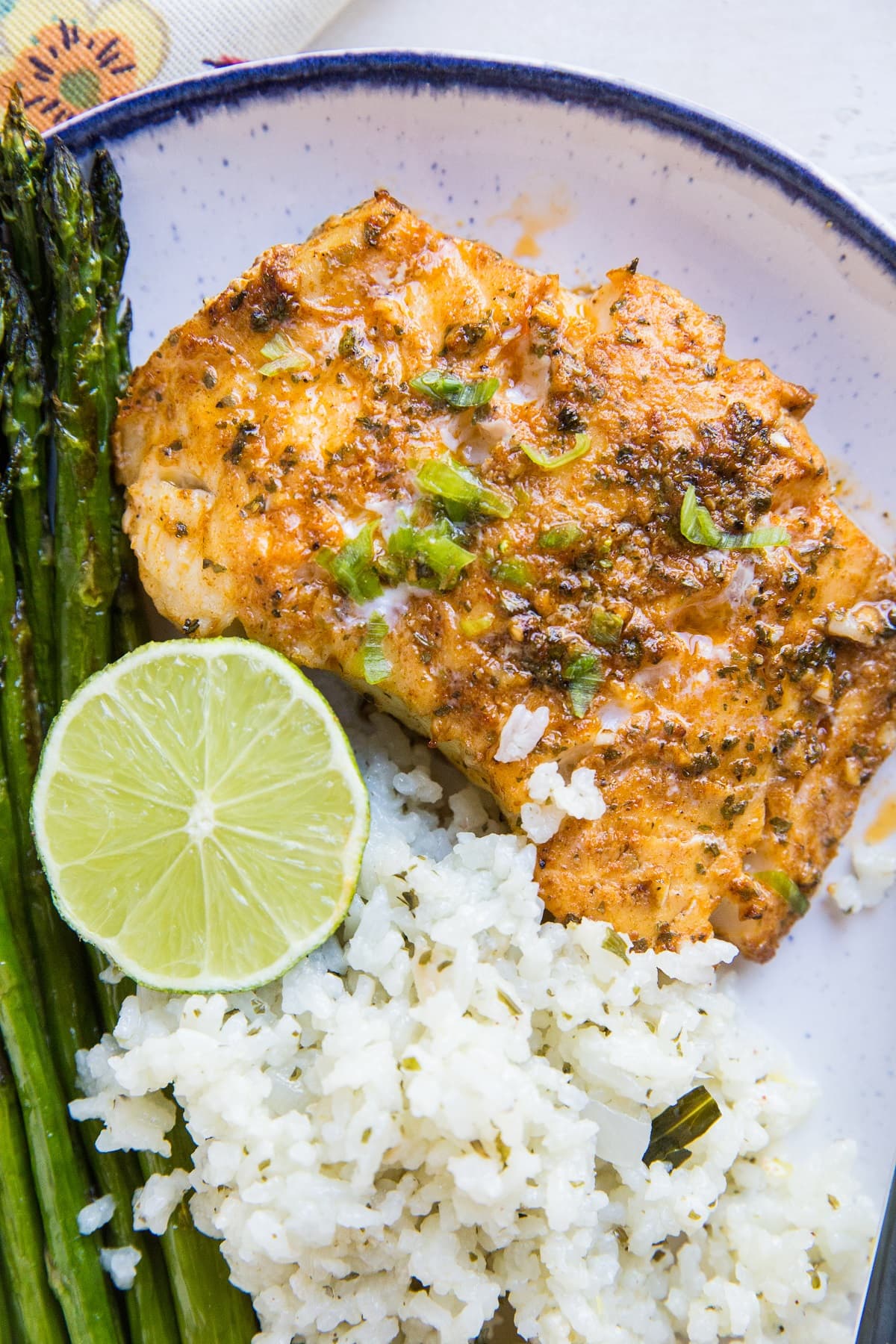 Plate of baked cod with asparagus and cauliflower rice. Ready to eat for dinner!