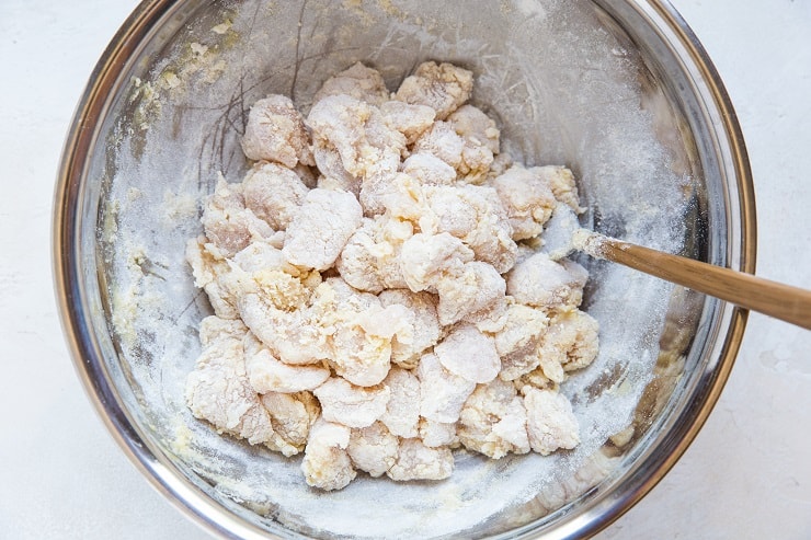 floured chicken in a mixing bowl