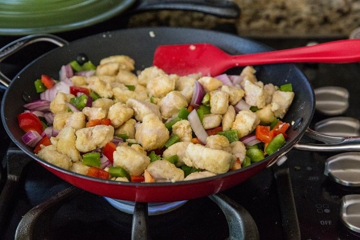 chicken and vegetables cooking in a skillet