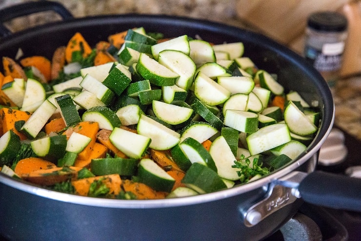 chopped broccoli, carrots, sweet potatoes and onion and zucchini cooking in a big skillet with seasonings