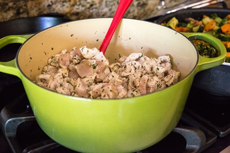 Chicken browning in a dutch oven with dried herbs