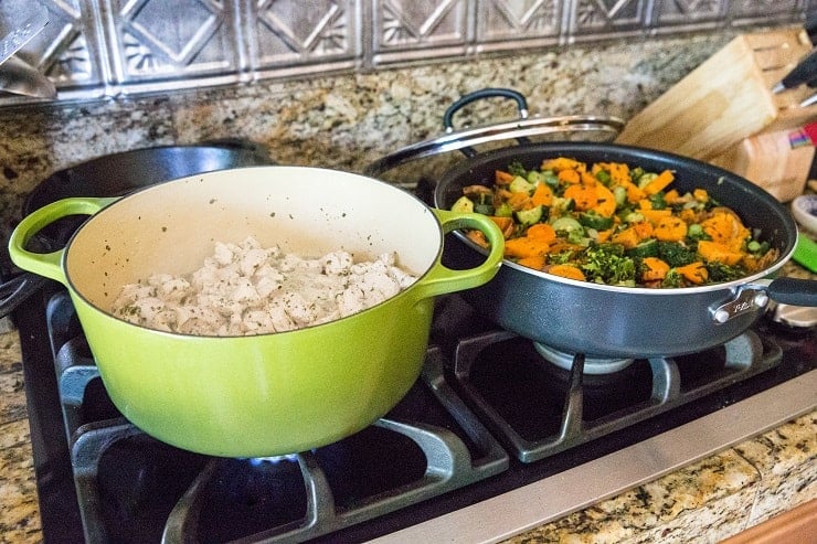 chicken and vegetables cooking in two pots on the stove top