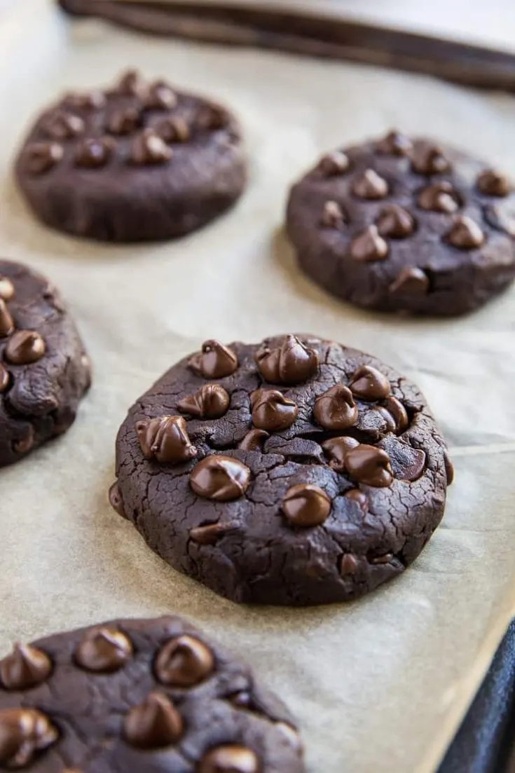 Chocolate black bean cookies with melting chocolate chips on top.