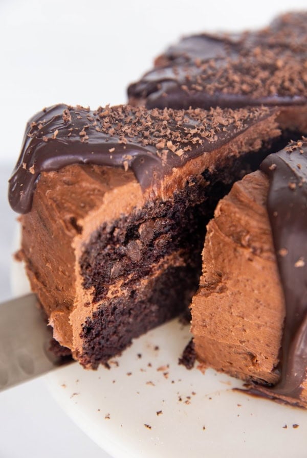Close up of a thick slice of chocolate cake being cut out of the full cake, about to be served.