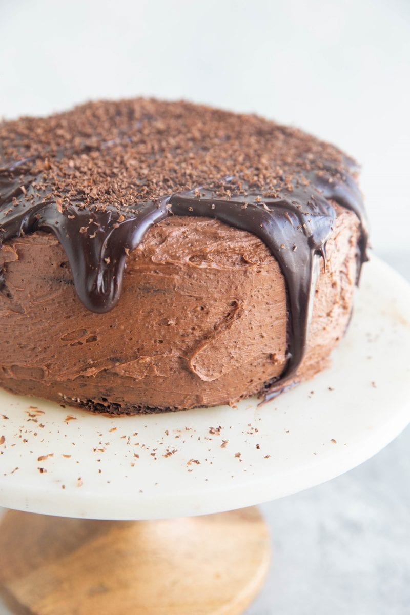 Rich, decadent gluten-free chocolate cake with chocolate buttercream and chocolate ganache sitting on a cake stand.