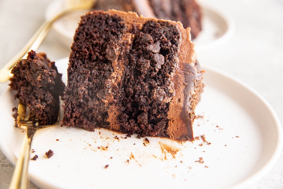 The Best Gluten-Free Chocolate Cake slice on a white plate with a bite taken out.