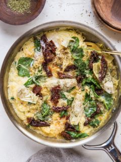 Stainless steel skillet of Creamy Tuscan Spaghetti Squash with grey napkin.