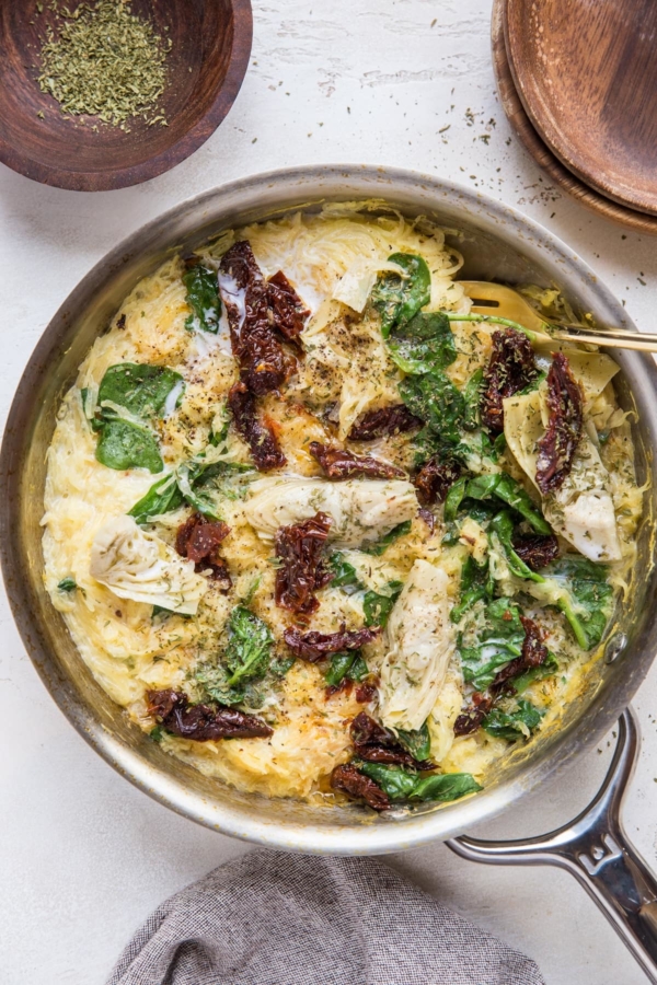 Stainless steel skillet of Creamy Tuscan Spaghetti Squash with grey napkin.