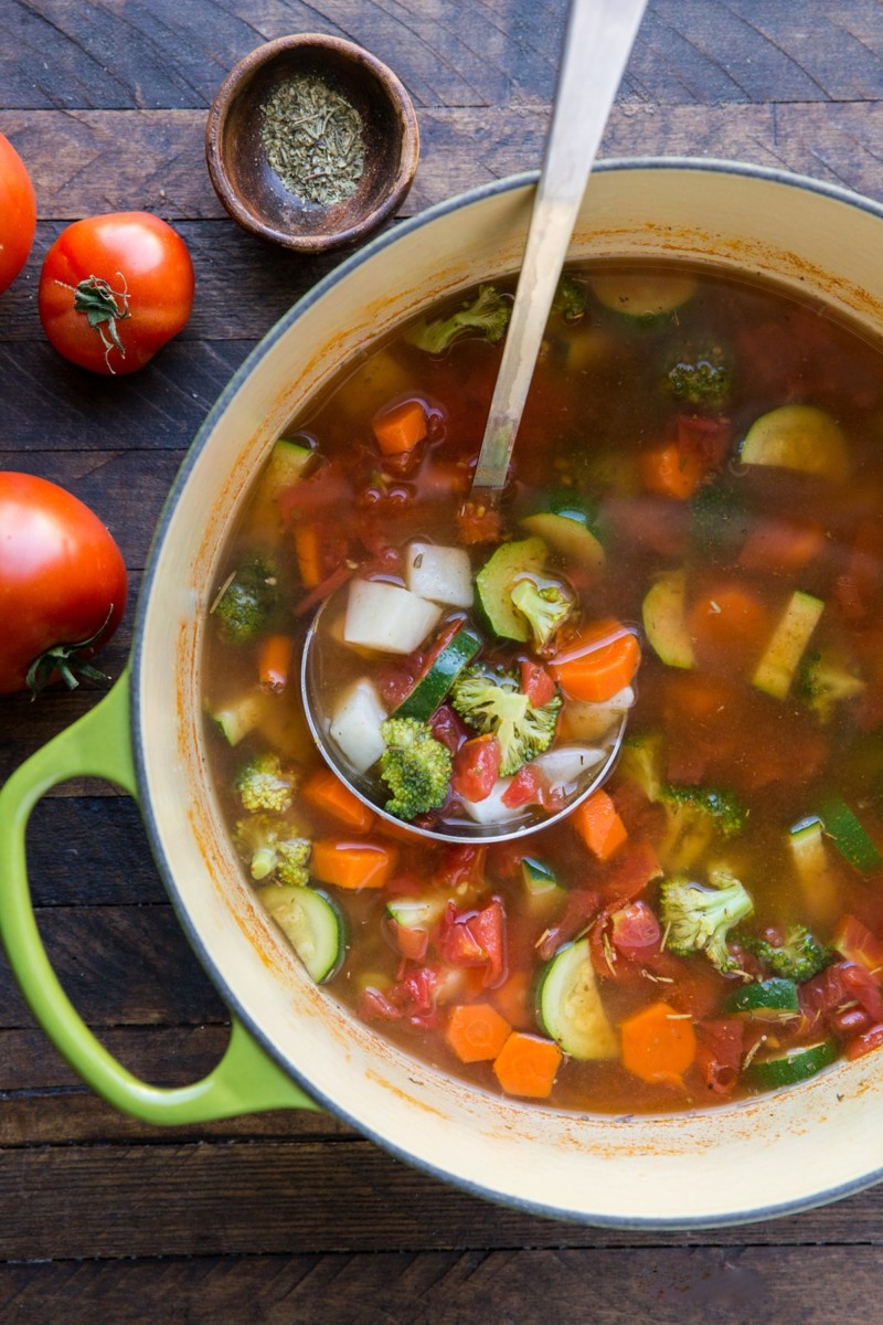 Big pot of homemade vegetable soup with a ladle inside the pot to serve the soup.