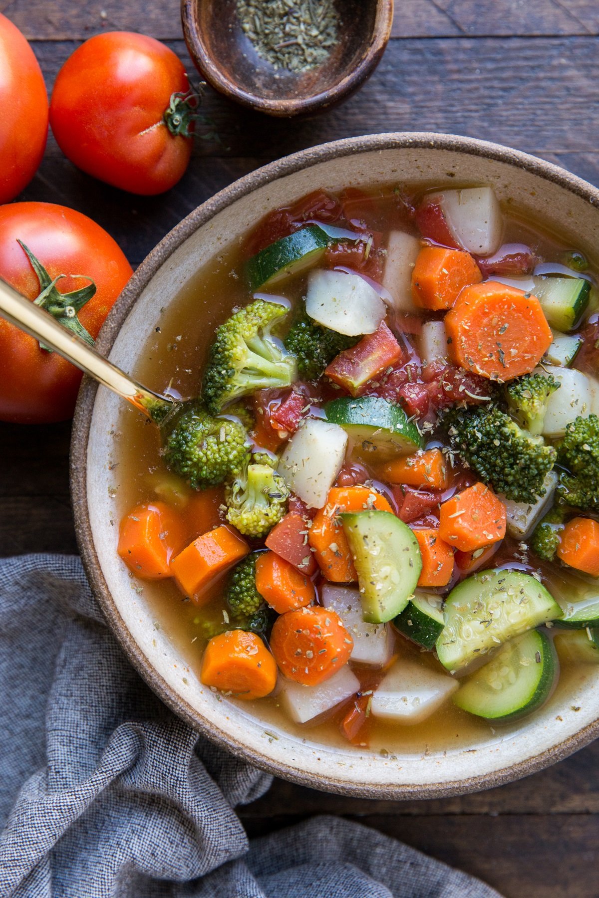 Big bowl of vegetable soup with a grey napkin to the side, ready to eat.