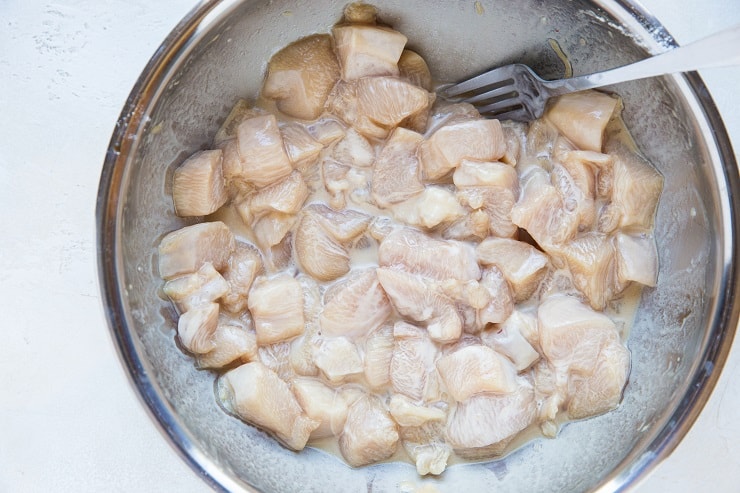 Chicken marinating in a mixing bowl for kung pao chicken