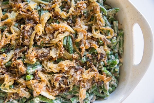 Green beans mixed with creamy sauce with caramelized onions in a baking dish, ready to go into the oven.