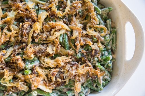 Green beans mixed with creamy sauce with caramelized onions in a baking dish, ready to go into the oven.