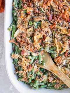 Top down image of a large casserole dish filled with healthy green bean casserole with caramelized onions and bacon on top.