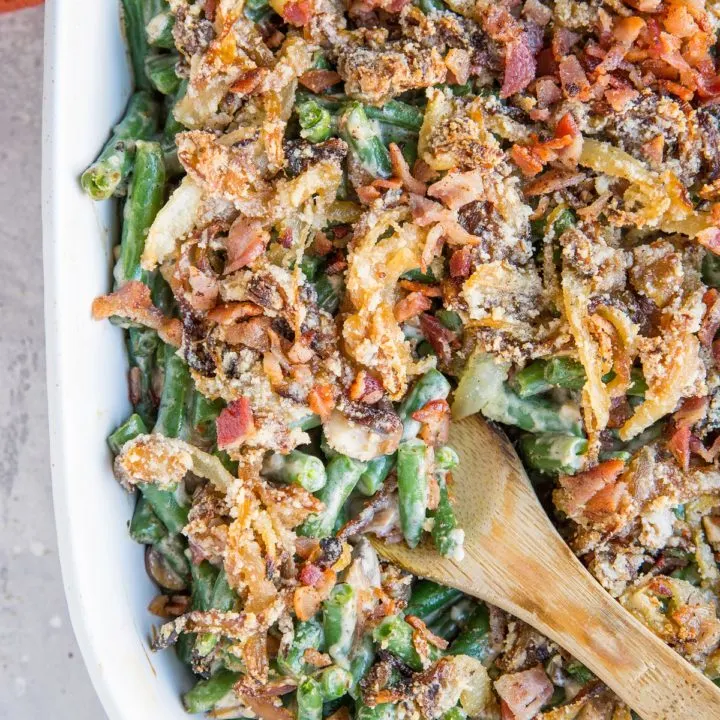 Top down image of a large casserole dish filled with healthy green bean casserole with caramelized onions and bacon on top.