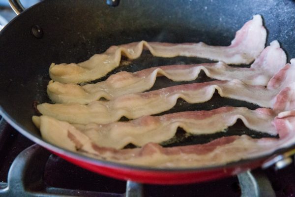 Bacon cooking in a skillet.