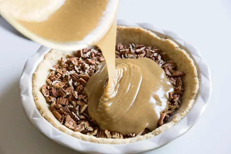Pour the keto caramel into the pie crust with the pecans