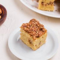 Slice of coffee cake on a plate with a fork to the side and more slices on a plate in the background.