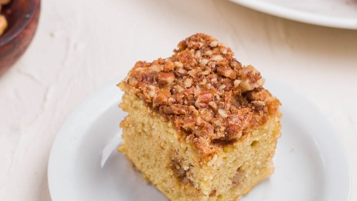 Slice of coffee cake on a plate with a fork to the side and more slices on a plate in the background.