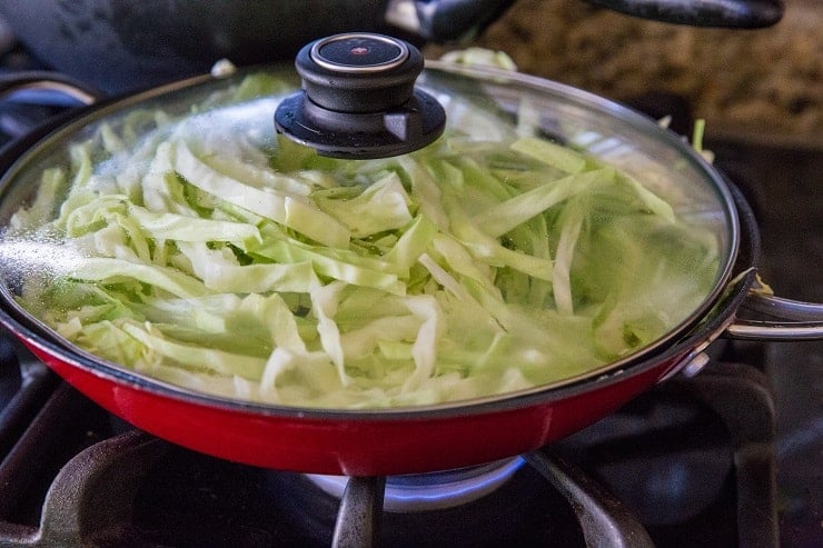 Cabbage cooking in a skillet with lid on