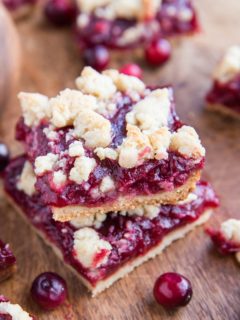 Stack of cranberry crumb bars on a cutting board.