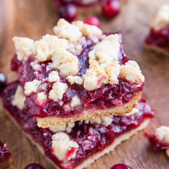 Stack of cranberry crumb bars on a cutting board.