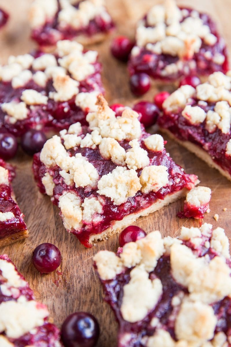 Close up image of sliced cranberry crumble bars on a wood cutting board