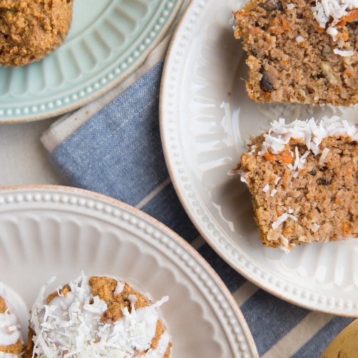 Top down photo of a healthy carrot cake muffin sliced in half sitting on a dark blue plate with a golden napkin