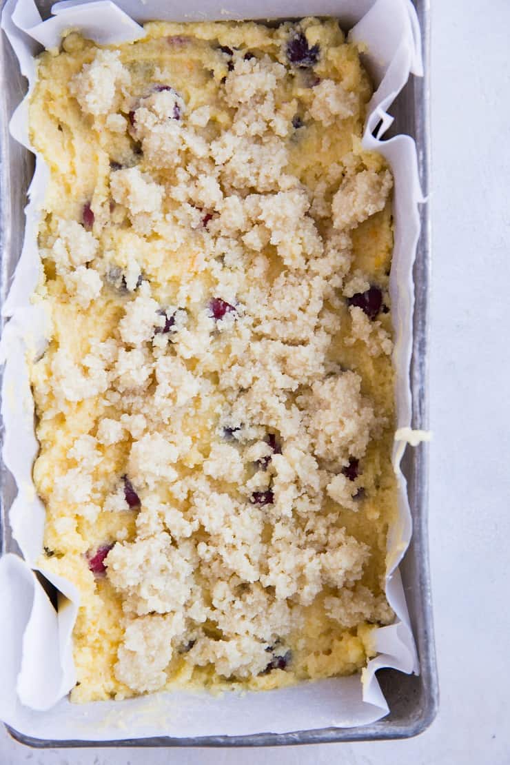 Transfer keto cranberry orange bread dough to a loaf pan and top with crumble topping