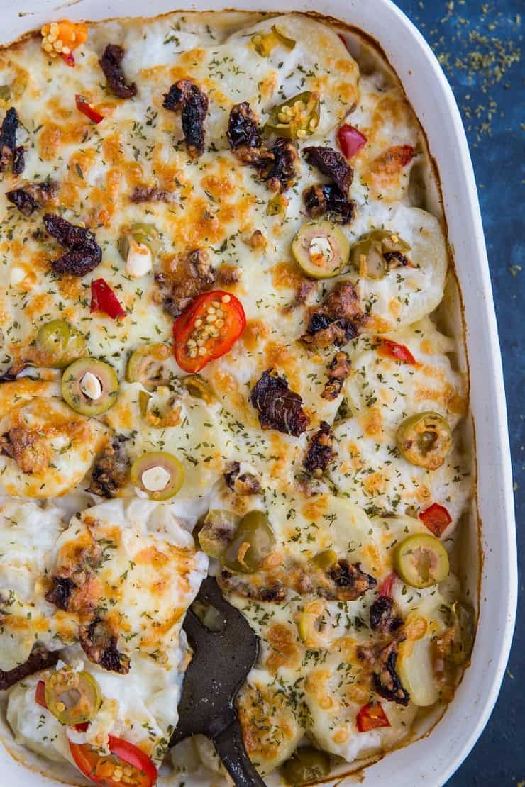 Mediterranean Scalloped Potatoes with sun-dried tomatoes, olives, and roasted bell peppers. A unique spin on classic scalloped potatoes for an amazing side dish!