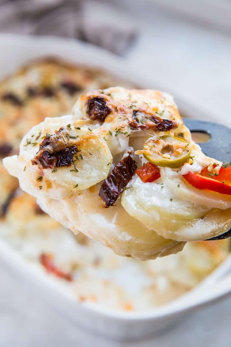 Mediterranean Scalloped Potatoes with sun-dried tomatoes, olives, and roasted bell peppers. A unique spin on classic scalloped potatoes for an amazing side dish!