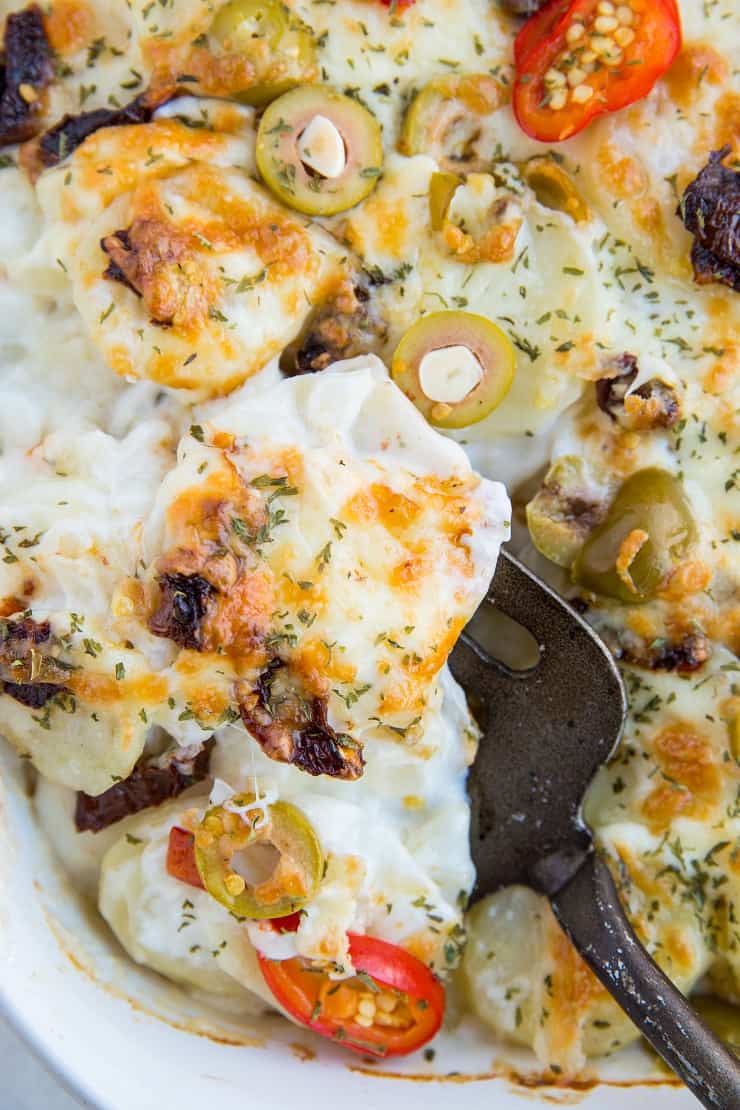 Mediterranean Scalloped Potatoes with sun-dried tomatoes, olives, and roasted bell peppers. A unique spin on classic scalloped potatoes for an amazing side dish!