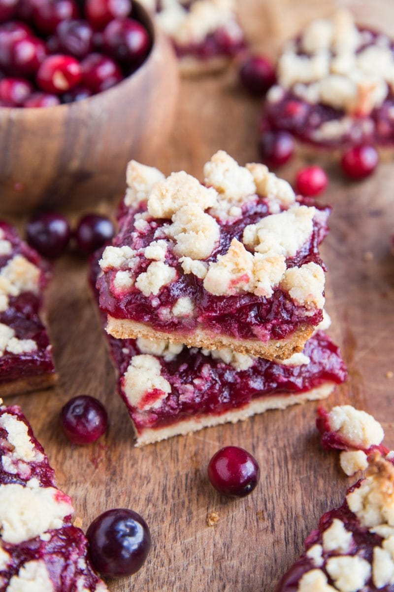 Stack of vegan cranberry crumb bars on wooden surface