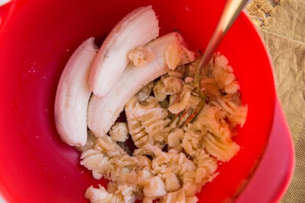 Bananas being mashed in a mixing bowl