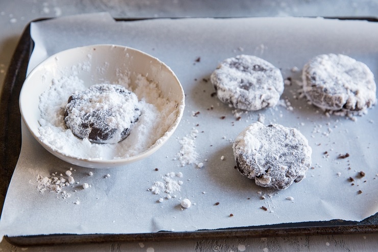 rolling crinkle cookies in confectioners sugar