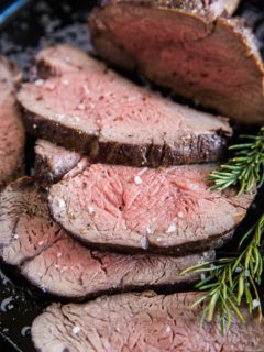 Medium-rare beef tenderloin sliced into slices in a cast iron skillet