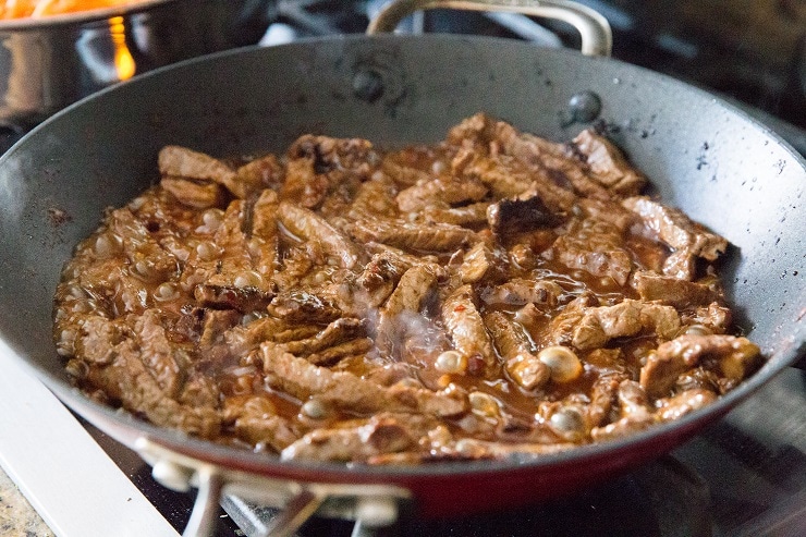 Szechuan beef cooking in a skillet