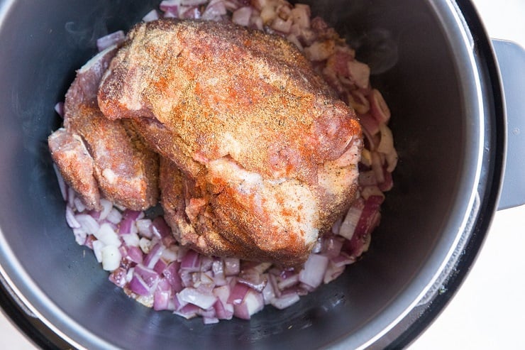 Sauté the onion in the Instant Pot then add the seasoned pork Shoulder