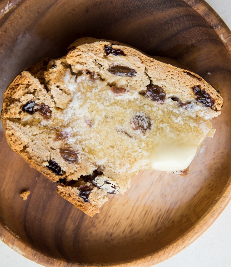 Slice of soda bread with melted butter on a wooden plate with a bite taken out