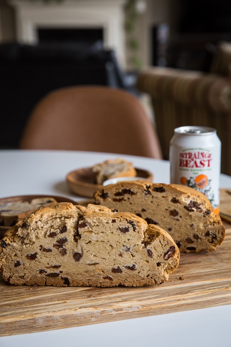 Loaf of Irish soda bread sliced in half on a cutting board with a Sierra Nevada Hard Kombucha off to the side